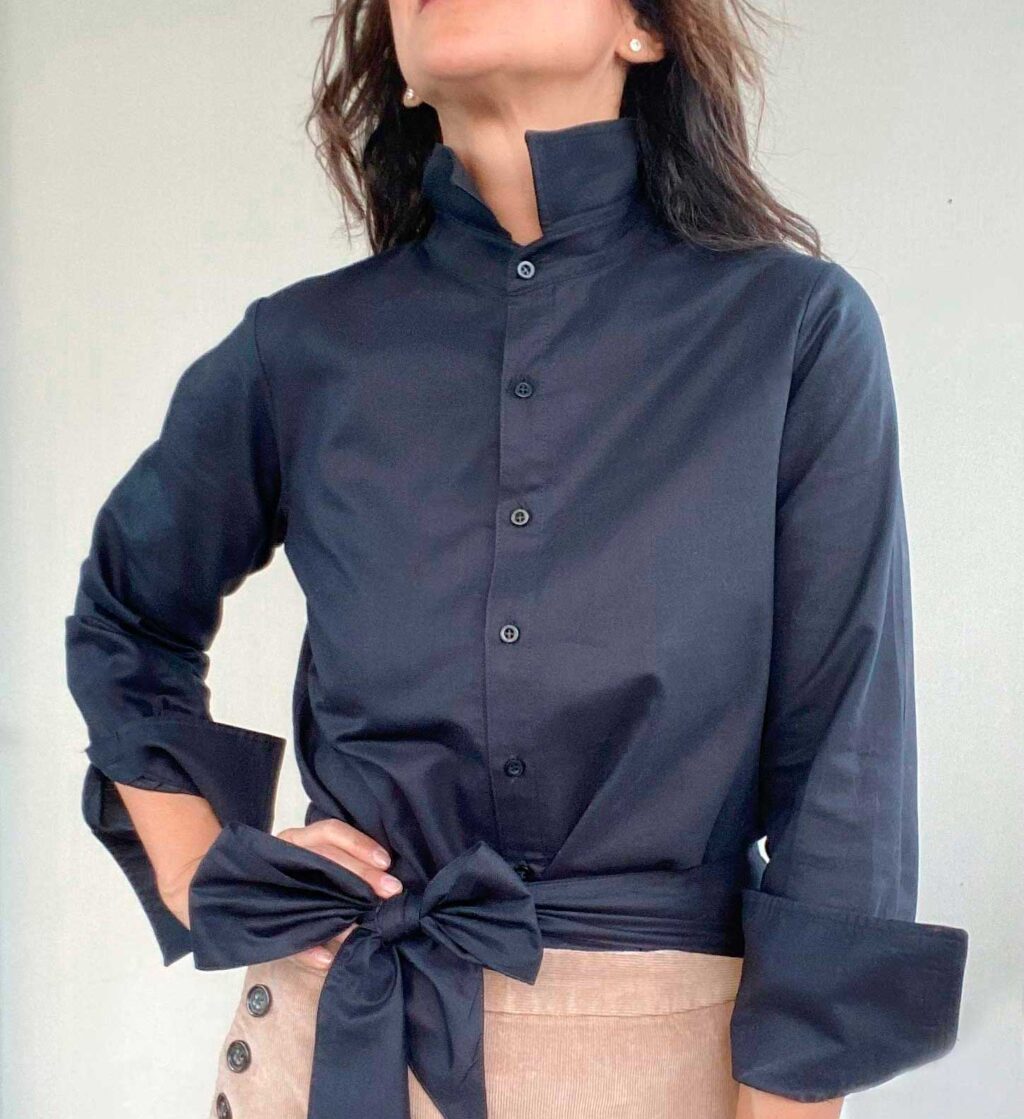 Clásica NEGRA es una camisa con cuello terminado en punta y mangas largas. Inspiración romántica, clásica y minimalista al mismo tiempo. Un modelo Versátil que puedes usar de diferentes formas según el estilo que quieras llevar, elegante, casual, deportiva. El detalle no va solo en su cuello y puños largos almidonados que te permiten jugar al recogerla o al lucirla en toda su extensión, sino que también, lleva un su listón que puedes combinar a tu estilo y darle tu personalidad.